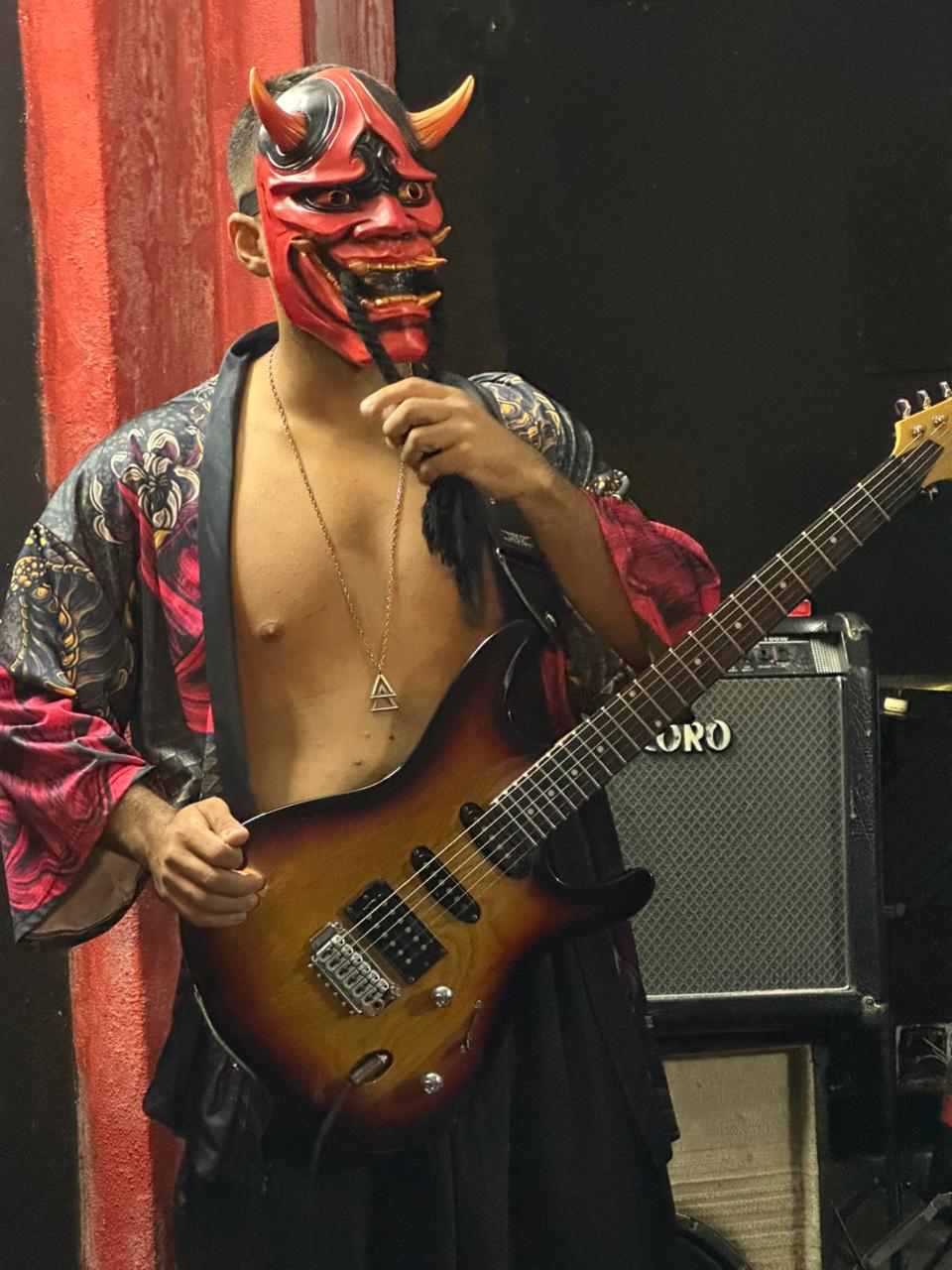 Red Oni com máscara vermelha de Oni e guitarra sunburst.